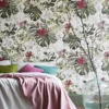 Summer Tropical Bloom Collection wallpaper depicting vibrant pink flowers and rich green leaves, creating a dynamic and lush backdrop for a cozy bedroom setting with colorful pillows.