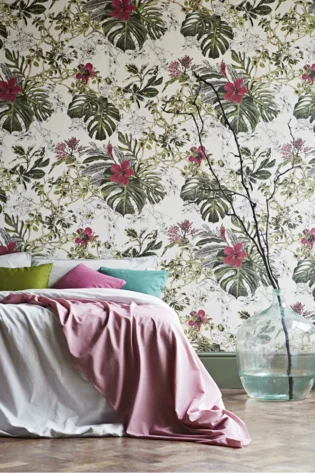Summer Tropical Bloom Collection wallpaper depicting vibrant pink flowers and rich green leaves, creating a dynamic and lush backdrop for a cozy bedroom setting with colorful pillows.