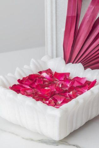 White Hover Square Candle Floater filled with striking pink rose petals beside a vibrant pink fan, creating a soothing and stylish atmosphere in any room.