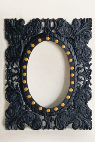 Black carved wood frame mirror with ornate detailing and gold accents, adding a luxurious touch to wall decor.