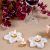 Delicate white marble 'Starlight' candle holders by Natural Handicrafts, with small tea candles lit, enhancing the floral ambiance on a textured tablecloth.