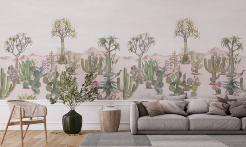 Panoramic view of the 'Desert Pink Sand' wallpaper in a modern living room, depicting a tranquil desert scene with cacti and distant mountains, enveloping the space in warmth and natural beauty.