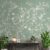 Wall adorned with Phoolbagh wallpaper, displaying a graceful floral pattern on a soft green background, evoking the charm of a peaceful botanical garden.